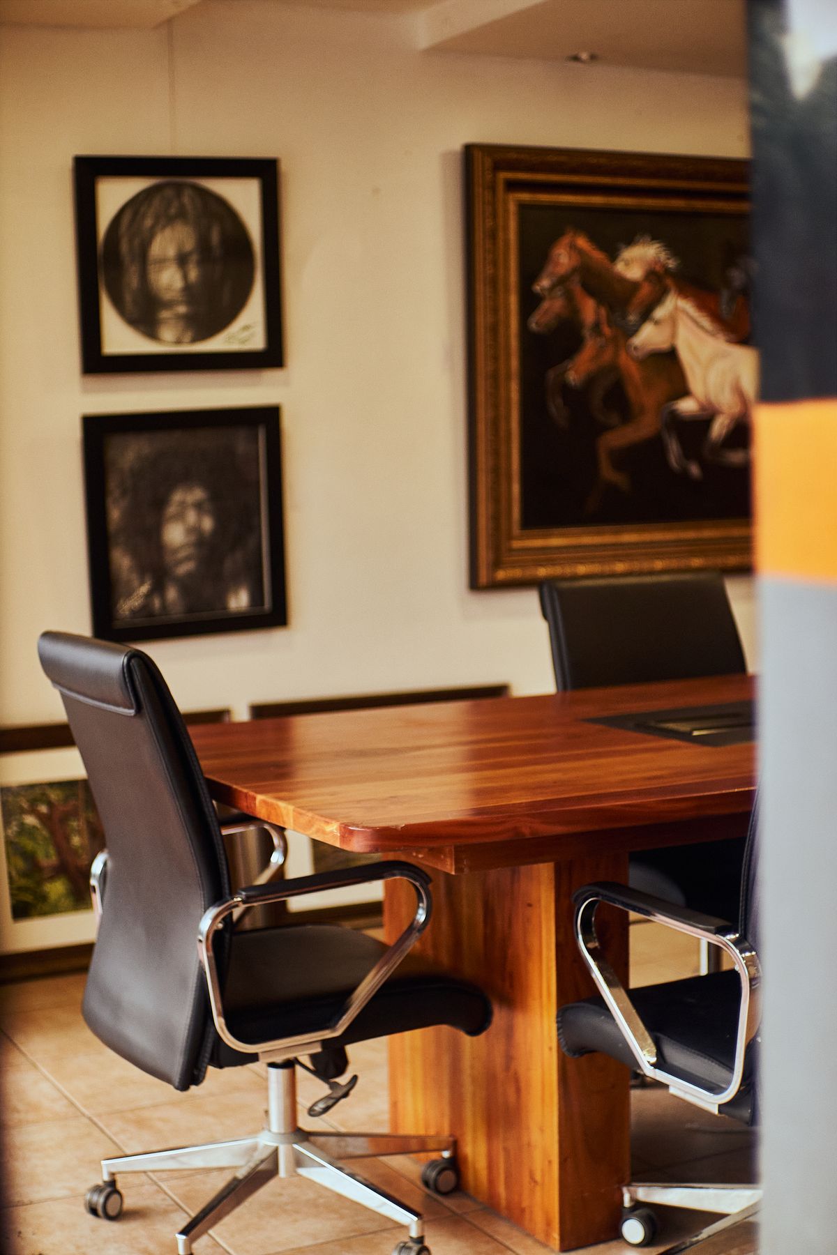Una sala de reuniones con mesa de madera, sillones de piel y obras de arte